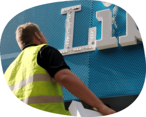 man in hi-vis looking at plastic sign.