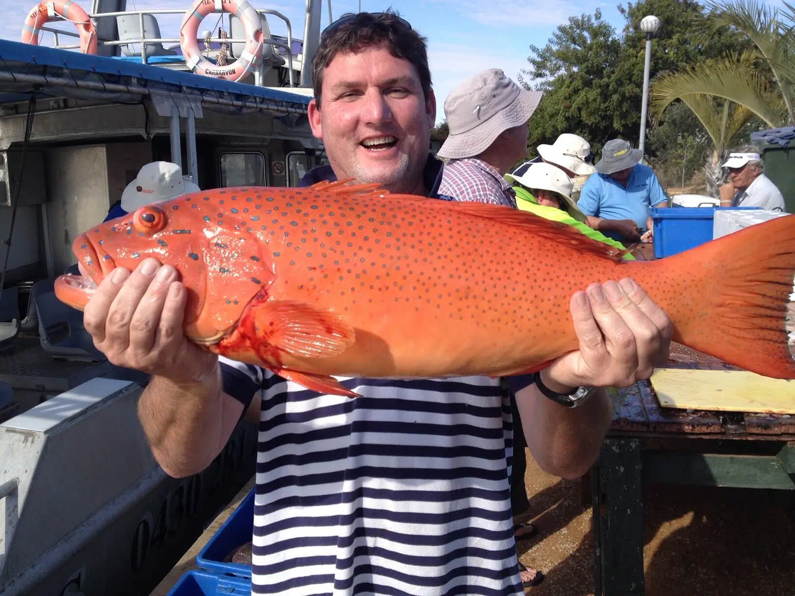 a man holding a large fish on a boat.