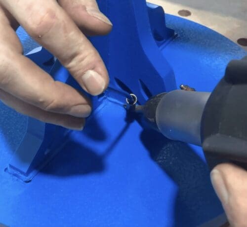 a person cutting a piece of metal with a pair of scissors.