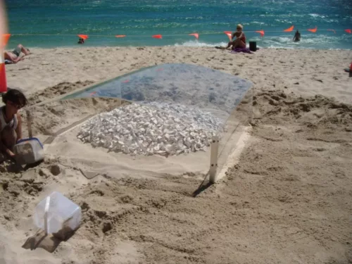 a woman sitting on a beach next to a glass table.