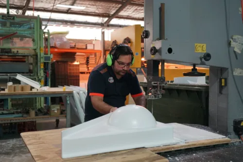 a man in a factory working on a white object.