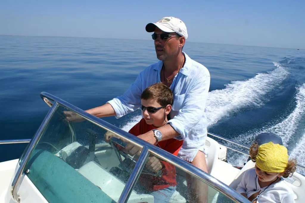 a man and two children on a boat in the ocean, protected by a custom acrylic plastic windscreen.