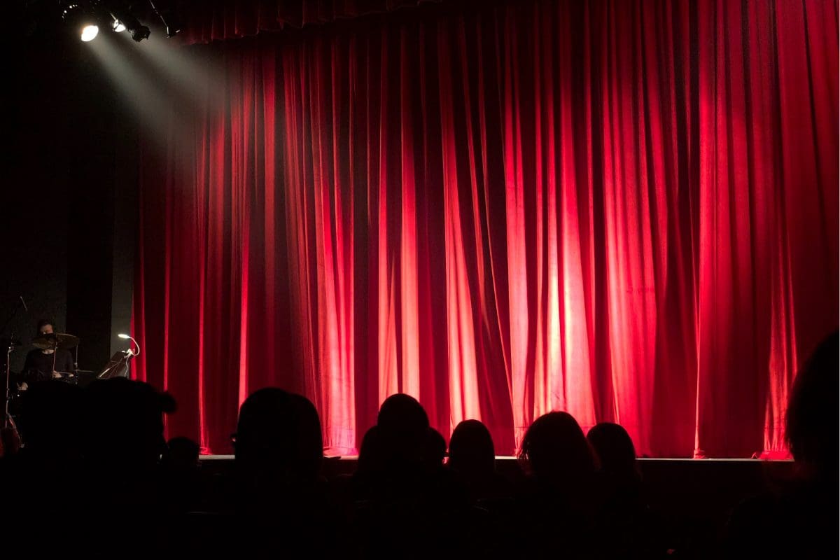 a stage with a red curtain and a spotlight.